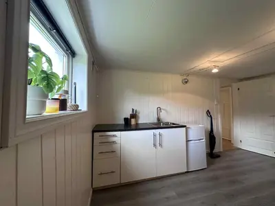 a kitchen with white cabinets and a sink and a window at Basement apartment in beautiful Volda in Volda