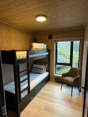 two bunk beds in a room with a chair and a window at Exclusive cabin with sauna and mountain view in Geilo in Hol