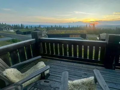 a wooden bench sitting on a deck with a view at Log Cabin With Views Of Jotunheimen in Øyer