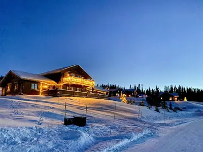 a large log cabin in the snow at night at Log Cabin With Views Of Jotunheimen in Øyer