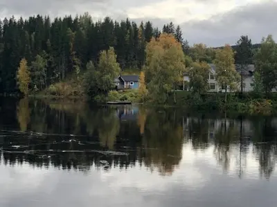 a house sitting on the shore of a lake at The Blue Cabin in Trysil