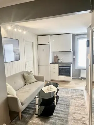 a living room with a couch and a kitchen at Koselig leilighet ved Solsiden in Trondheim