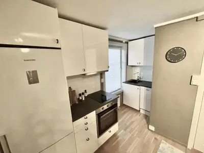 a kitchen with white cabinets and a clock on the wall at Koselig leilighet ved Solsiden in Trondheim
