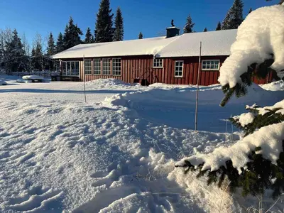 a snow covered yard in front of a red building at Very central and by the lake Sjusjøen in Ringsaker