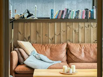 a living room with a brown couch and a shelf with books at Modern Cabin With Mountain Views In Rauland in Rauland