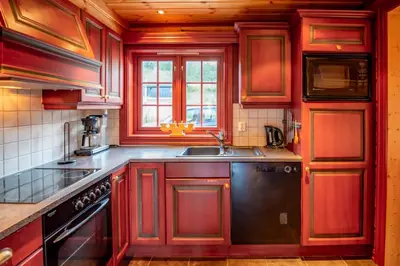 a kitchen with red wooden cabinets and a sink at Lisetra 716B in Trysil
