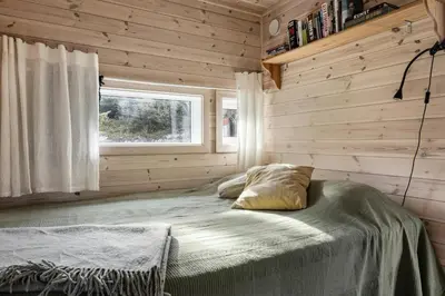 a bed in a wooden room with a window at Family Cabin With Views Over Hadeland in Lunner