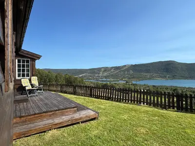 a wooden deck with two chairs on top of a house at Fjellro-Geilo Cabin Retreat in Geilo
