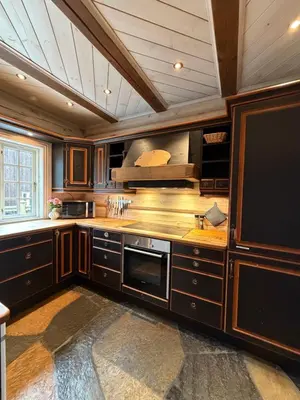 a large kitchen with wooden cabinets and a tv at Log cabin at Hafjell in Øyer