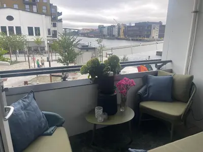a balcony with two chairs and a table with flowers at Sentrumsnær leilighet Bergen in Bergen