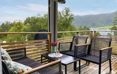 a patio with three chairs and a table on a deck at Gorgeous Home In Lavik With House Sea View in Lavik