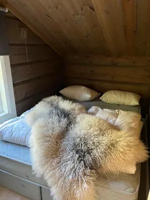 a bed with a furry blanket on top of it at ØRNENIPA LODGE- flott hytte med 6 sov, 2 bad og beste beliggenhet in Gaustablikk