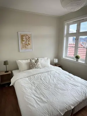 a bedroom with a large white bed with two windows at Våkn opp til fantastisk utsikt in Bergen
