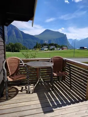 a table and two chairs on a deck with mountains at Mountain view cabin in Torvik