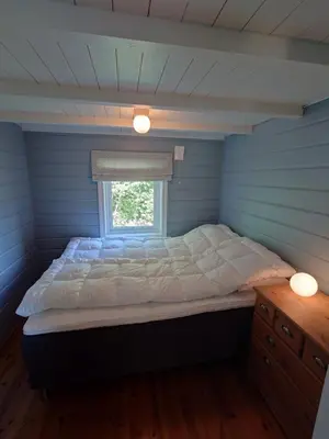 a bed in a blue room with a window at Mountain view cabin in Torvik