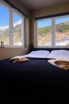 a bedroom with a bed with two large windows at Trolltunga Stay in Odda