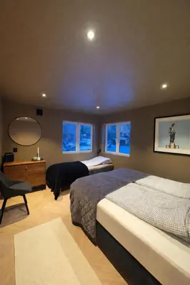 a bedroom with two beds and a desk with a mirror at Trolltunga Stay in Odda