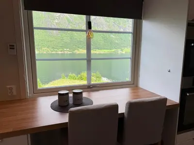 a table with chairs and a window with a view of a lake at Vistdal Panoramic View in Myklebostad