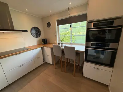 a kitchen with white cabinets and a table with chairs at Vistdal Panoramic View in Myklebostad