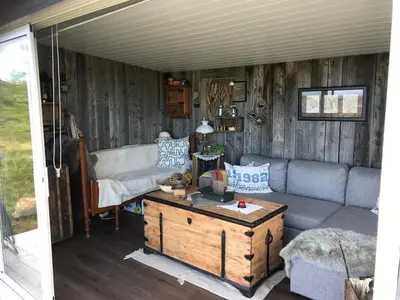 a living room with a couch and a table at Cabin with stunning views and outdoor jacuzzie in Leset