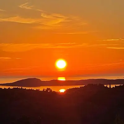 a sunset with the sun setting over the mountains at Cabin with stunning views and outdoor jacuzzie in Leset