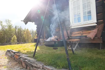 a bbq grill with a chicken cooking on it at Nydelig hyttetun på Torpoåsen in Torpo