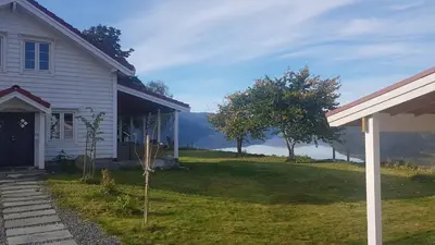 a white house with a yard with a tree at House with oceanview in Stryn