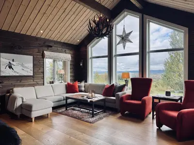 a living room with a couch and chairs and windows at Spacious cabin in the mountains in Gol