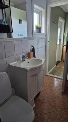 a bathroom with a sink and a toilet and a mirror at Charming family house with beautiful views! in Askøy