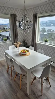 a white dining room table with chairs and a chandelier at Charming family house with beautiful views! in Askøy