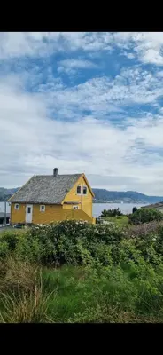 a yellow house sitting on top of a grass field at Charming family house with beautiful views! in Askøy
