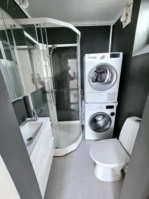 a bathroom with a washing machine and a washer at Modern City Apartment with garden and view in Molde