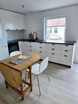 a kitchen with a wooden table and white cabinets at Modern City Apartment with garden and view in Molde