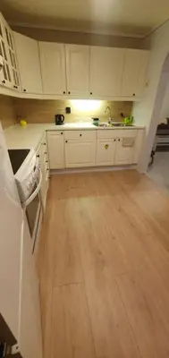 a kitchen with white cabinets and a wooden floor at Fotlandsvåg Guest Apartment in Bernes