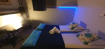 a room with two beds and a table with a lamp at Fotlandsvåg Guest Apartment in Bernes