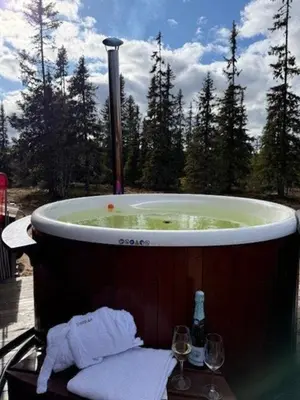 a hot tub with a table and two glasses of wine at Timber Cabin With Wood-Fired Hot Tub In Trysil in Trysil