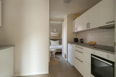a kitchen with white cabinets and a bed in the background at Bergen City Retreat - Steps from Bryggen - Norwegians Minimum Age 25 in Bergen