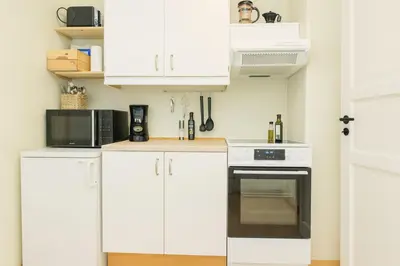 a kitchen with white cabinets and a black oven at Delightful Bryggen Apartment - Norwegians Minimum Age 25 in Bergen