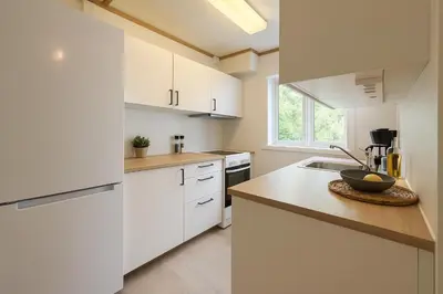 a white kitchen with white cabinets and a sink at Quartet Bryggen Central - Quiet and Cozy - Norwegians Minimum Age 25 in Bergen