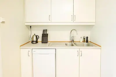 a kitchen with white cabinets and a sink at Quartet Bryggen Central - Quiet and Cozy - Norwegians Minimum Age 25 in Bergen