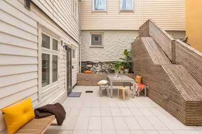 a patio with a bench and a table next to a house at Cozy loft with king bed in the middle of town in Bergen
