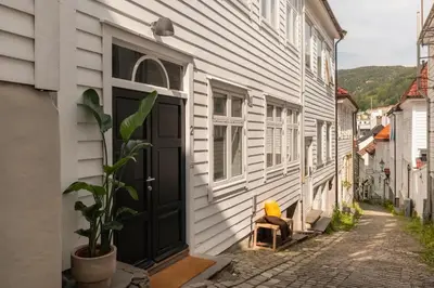 a house with a black door and a chair on a street at Cozy loft with king bed in the middle of town in Bergen