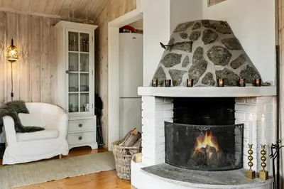 a fireplace in a living room with a white couch and a chair at Charming Cabin By Nesfjellet Ski Resort in Nesbyen