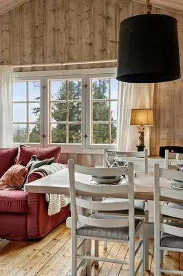 a dining room with a table and a red couch at Charming Cabin By Nesfjellet Ski Resort in Nesbyen