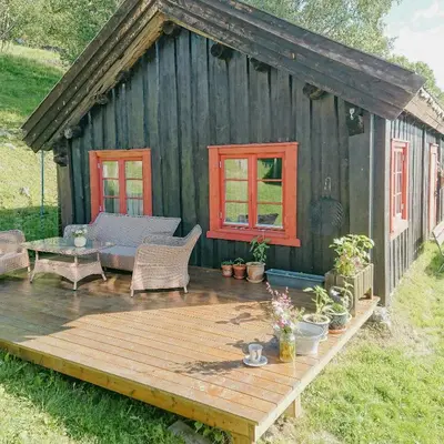 a wooden deck in front of a black shed at Restored Cabin From 1852 In Bergsjø Area in Ål