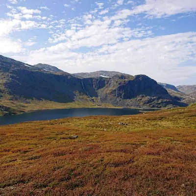 a lake in the middle of a field with mountains at Restored Cabin From 1852 In Bergsjø Area in Ål
