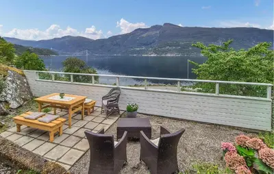 a patio with a table and chairs and a view of a lake at Awesome Home In Eidfjord With House Sea View in Eidfjord