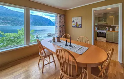 a dining room with a table and chairs and a large window at Awesome Home In Eidfjord With House Sea View in Eidfjord