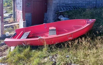 a red boat sitting in the grass next to a building at Stunning Home In Korssund With Wifi in Korssund
