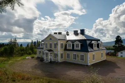 a large yellow house with a black roof at Villa Grøndalen Gård in Trysil